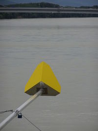 Yellow umbrella on wet pole by sea