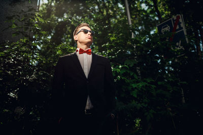 Portrait of young man standing against trees