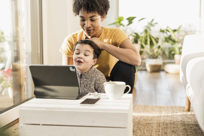 Mother and son using digital tablet while sitting at home