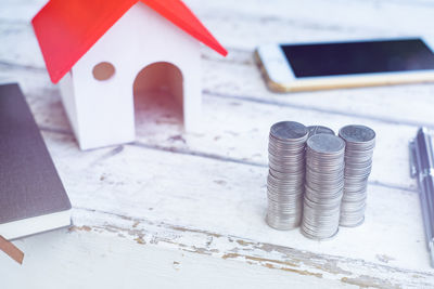 High angle view of stacked coins with model home on table