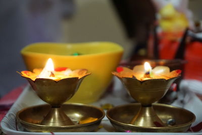 Close-up of illuminated diyas in tray at home