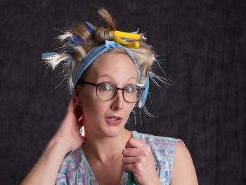 Portrait of woman wearing hair curlers against wall