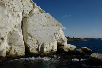 Rock formations by sea against sky