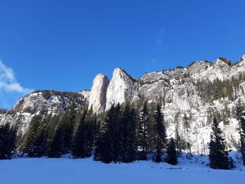 Low angle view of snowcapped mountains against blue sky