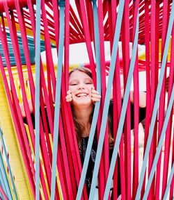 Portrait of smiling girl standing by colorful ropes