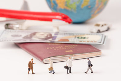 Close-up of figurines with passport and currency on table