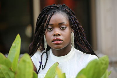 Portrait of young woman against plants outdoors