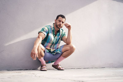Mature man wearing socks crouching near wall