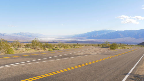 Road by mountains against sky