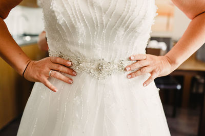 Midsection of bride with arms akimbo standing at home