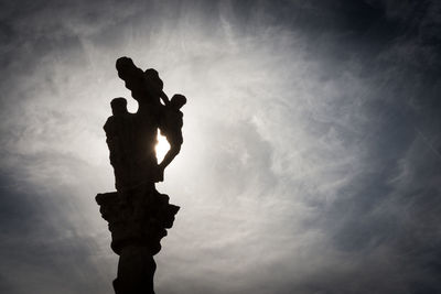 Low angle view of silhouette statue against sky