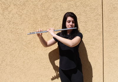 Full length of young woman standing against wall