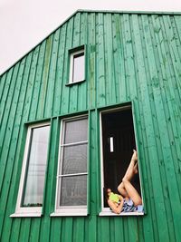 Woman lying on window of building