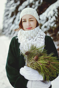 Redhead beautiful woman in green sweater and white gloves walking in the frozen winter forest.