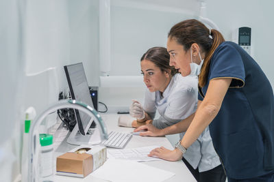 Side view of medical practitioners browsing data on modern computer while working in lab of modern hospital together