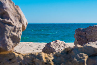 Rocks on beach against clear blue sky