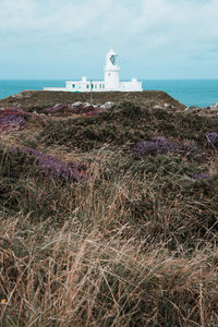 Lighthouse by sea against sky