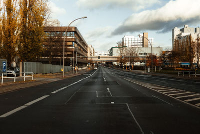 Road by buildings in city against sky