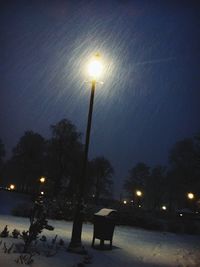 Illuminated street light against sky during winter at night