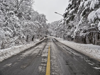 Empty road along snow covered trees