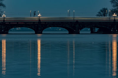 Train on arch bridge over river against sky at night