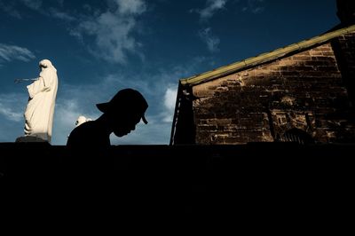 Low angle view of silhouette statue against sky