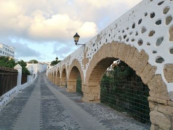 View of old arches building against cloudy sky