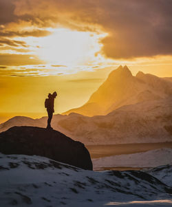 Silhouette man standing on mountain against sky during sunset
