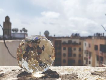 Close-up of crystal ball on land against sky in city
