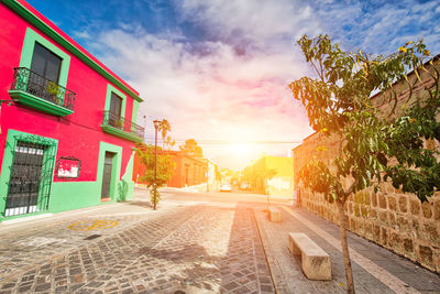 Street amidst buildings against sky during sunset