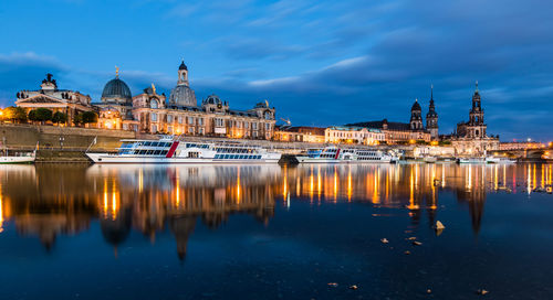 Boats moored on river by dresden frauenkirche at dusk