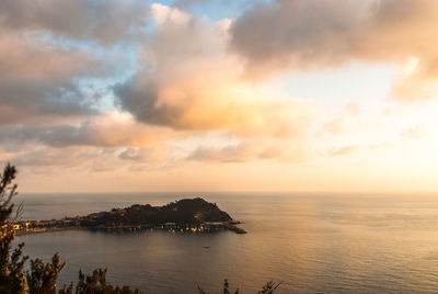 Scenic view of sea against cloudy sky at sunset