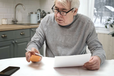 Senior man checking calculating personal finance at home, feeling stress from money problem