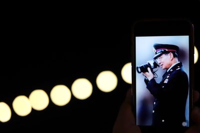 Man photographing illuminated smart phone at night