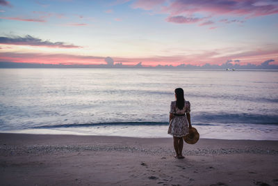 Rear view of woman on beach during sunset