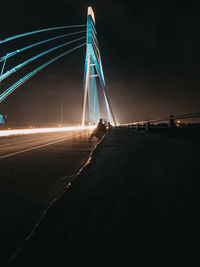 Light trails on bridge against sky at night