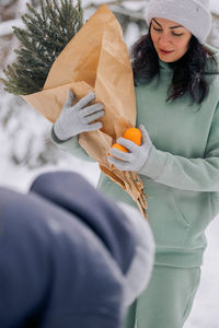 Happy couple playing winter game in forest outdoors. boyfriend gives girlfriend bouquet of spruce 