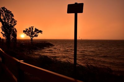 Silhouette plants by sea against sky during sunset