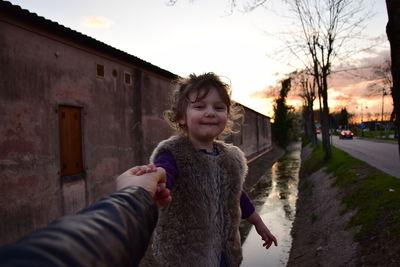 Cropped image of parent holding hand of daughter during sunset