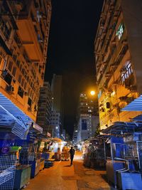 People walking on illuminated street amidst buildings at night