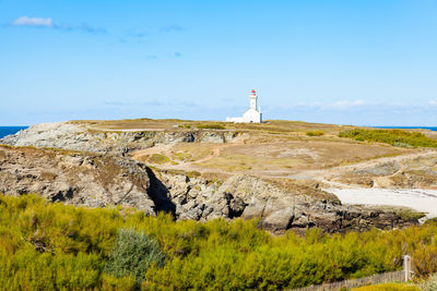 Lighthouse on street amidst buildings against sky