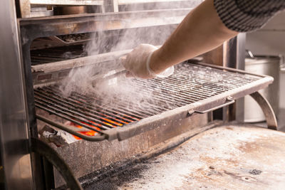 Midsection of person working on barbecue grill