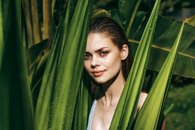 Portrait of young woman standing against plants