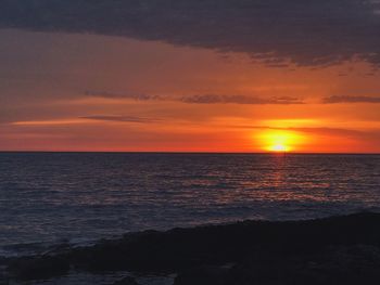 Scenic view of sea against dramatic sky during sunset