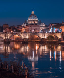 Illuminated bridge over river in city at night