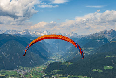 Person paragliding over mountain against sky