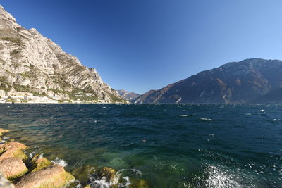 Scenic view of sea and mountains against blue sky