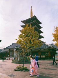 People at temple outside building against sky