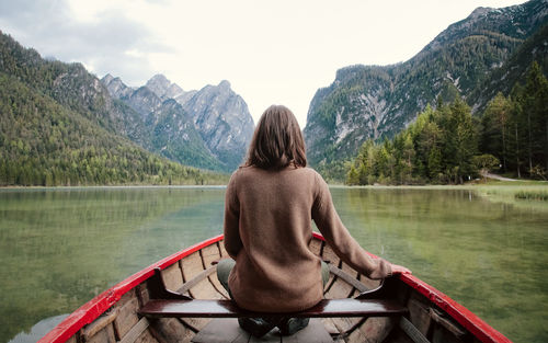 Rear view of woman boating on lake against mountains