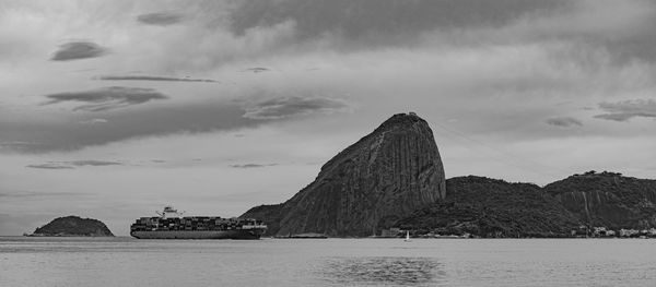 Photo of sugarloaf mountain with a cargo ship passing in front of it in guanabara bay